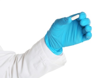 Doctor in medical glove holding pill on white background