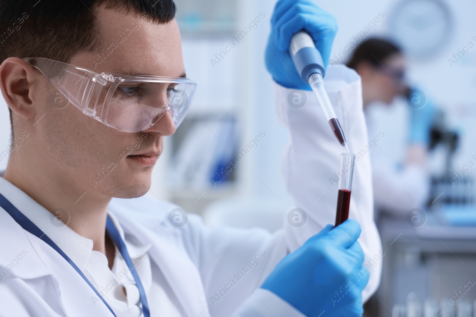 Photo of Scientist dripping sample into test tube in laboratory, closeup