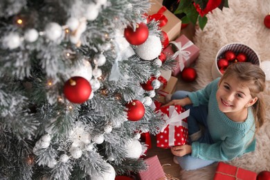 Cute little girl with Christmas present at home, above view