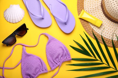 Photo of Flat lay composition with sunscreen and beach accessories on yellow background