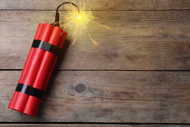 Image of Dynamite bomb with lit fuse on wooden table, top view. Space for text