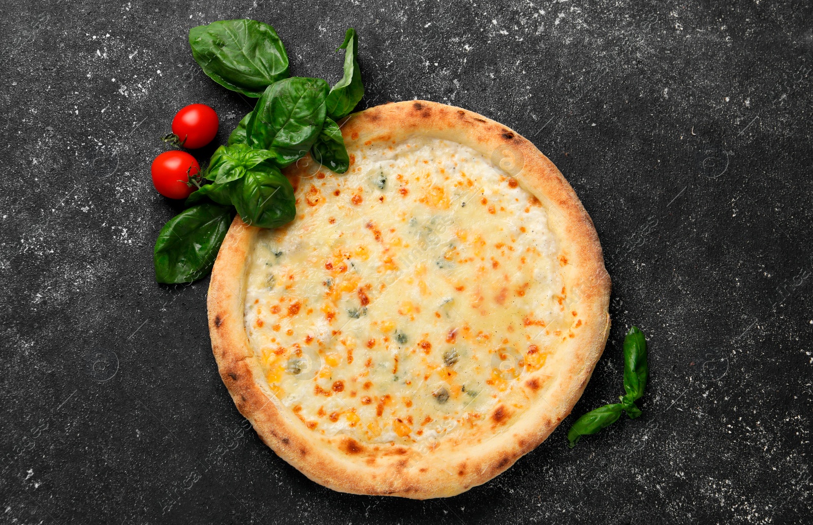 Photo of Delicious cheese pizza, basil and tomatoes on black textured table, flat lay