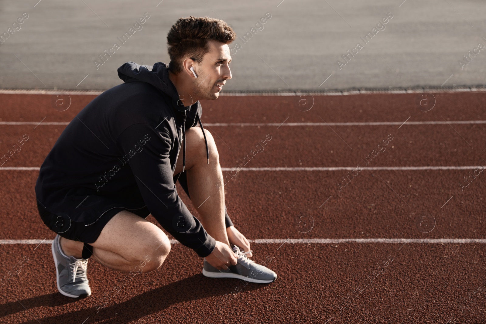 Photo of Young sportsman with wireless earphones at stadium