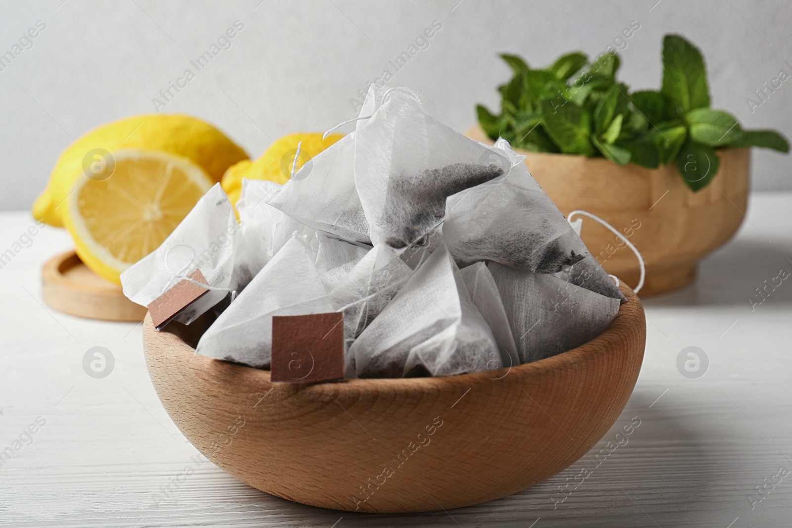 Photo of Tea bags, mint and lemons on white wooden table, closeup
