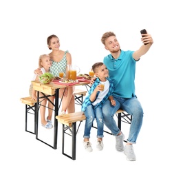 Photo of Happy family taking selfie at picnic table on white background