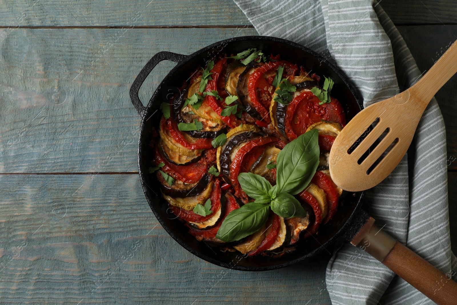 Photo of Delicious ratatouille on light blue wooden table, top view. Space for text