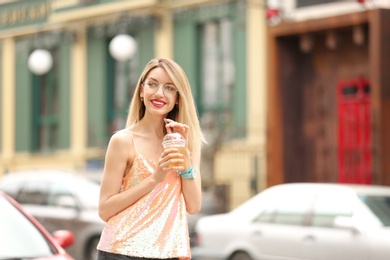 Young woman with cup of tasty lemonade outdoors