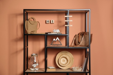 Photo of Stylish shelving unit with decorative elements near color wall. Interior design