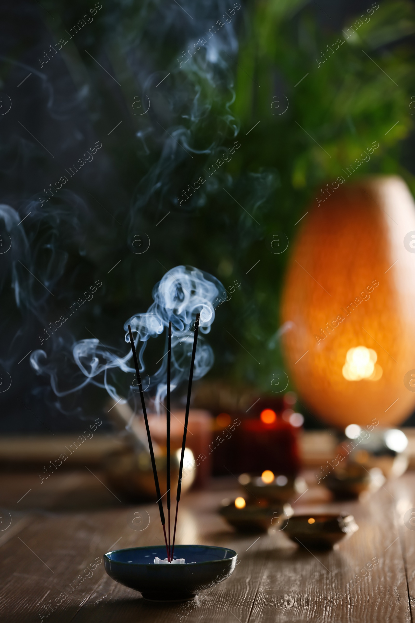 Photo of Incense sticks smoldering on wooden table in room