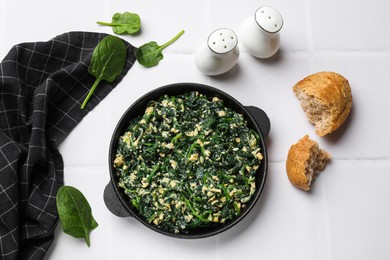 Photo of Tasty spinach dip with eggs in dish served on white tiled table, flat lay