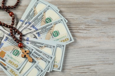 Cross and money on wooden table, top view. Space for text