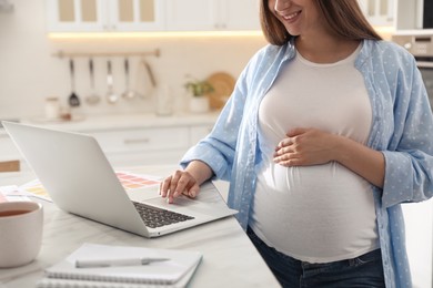 Photo of Pregnant woman working in kitchen at home, closeup. Maternity leave