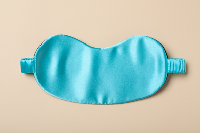 Photo of Turquoise sleeping mask on yellow background, top view. Bedtime accessory