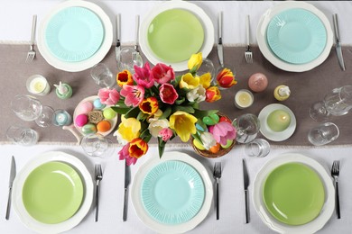 Easter celebration. Festive table setting with beautiful flowers and painted eggs, flat lay