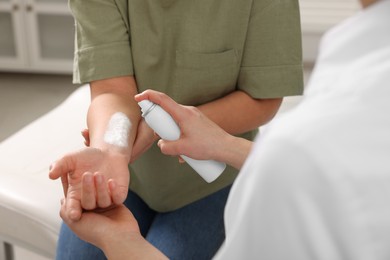 Doctor applying panthenol onto patient's burned hand in clinic, closeup