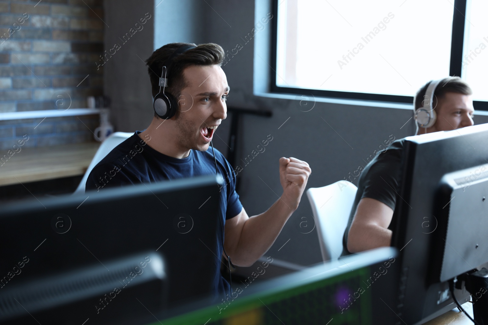 Photo of Emotional man playing video game in internet cafe