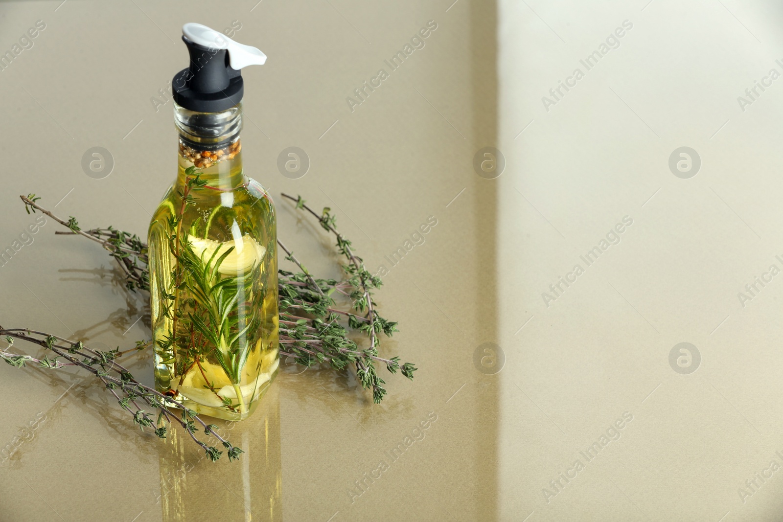 Photo of Cooking oil with spices and herbs in bottle on colorful table. Space for text