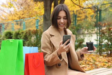 Photo of Special Promotion. Happy young woman with smartphone and cup of drink in park