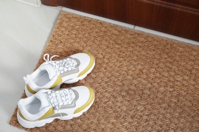 Photo of New clean mat with shoes near entrance door