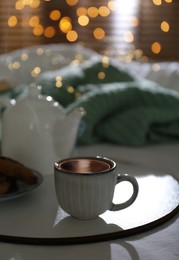 Photo of Tray with cup of hot tea and teapot on bed indoors