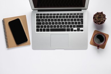 Modern laptop, houseplant, smartphone and cup of coffee on white table, flat lay. Space for text