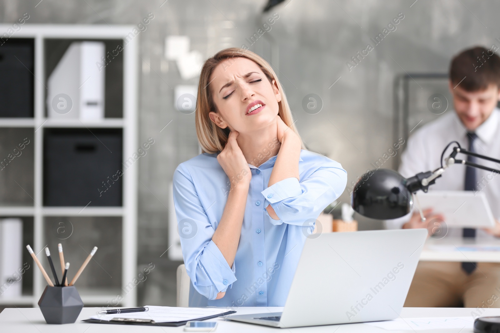 Photo of Young woman suffering from neck pain in office