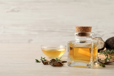 Photo of Fresh truffle oil and thyme on wooden table, space for text