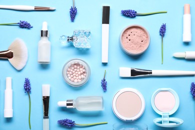 Photo of Flat lay composition with different makeup products and beautiful spring flowers on light blue background