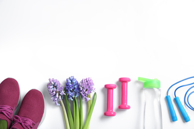 Composition with spring flowers and sports items on white background, flat lay. Space for text