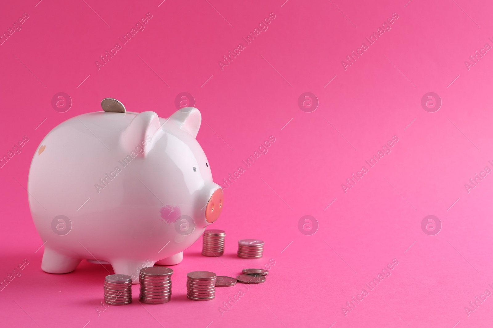 Photo of Financial savings. Piggy bank and coins on pink background, space for text