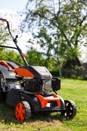 Photo of Modern lawn mower on green grass in garden, closeup