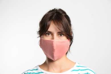 Young woman in protective face mask on light background