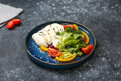 Photo of Plate with delicious mozzarella salad on dark grey table. Food stylist