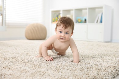 Cute baby boy crawling on carpet at home