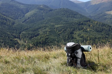 Backpack and sleeping pad in mountains on sunny day, space for text