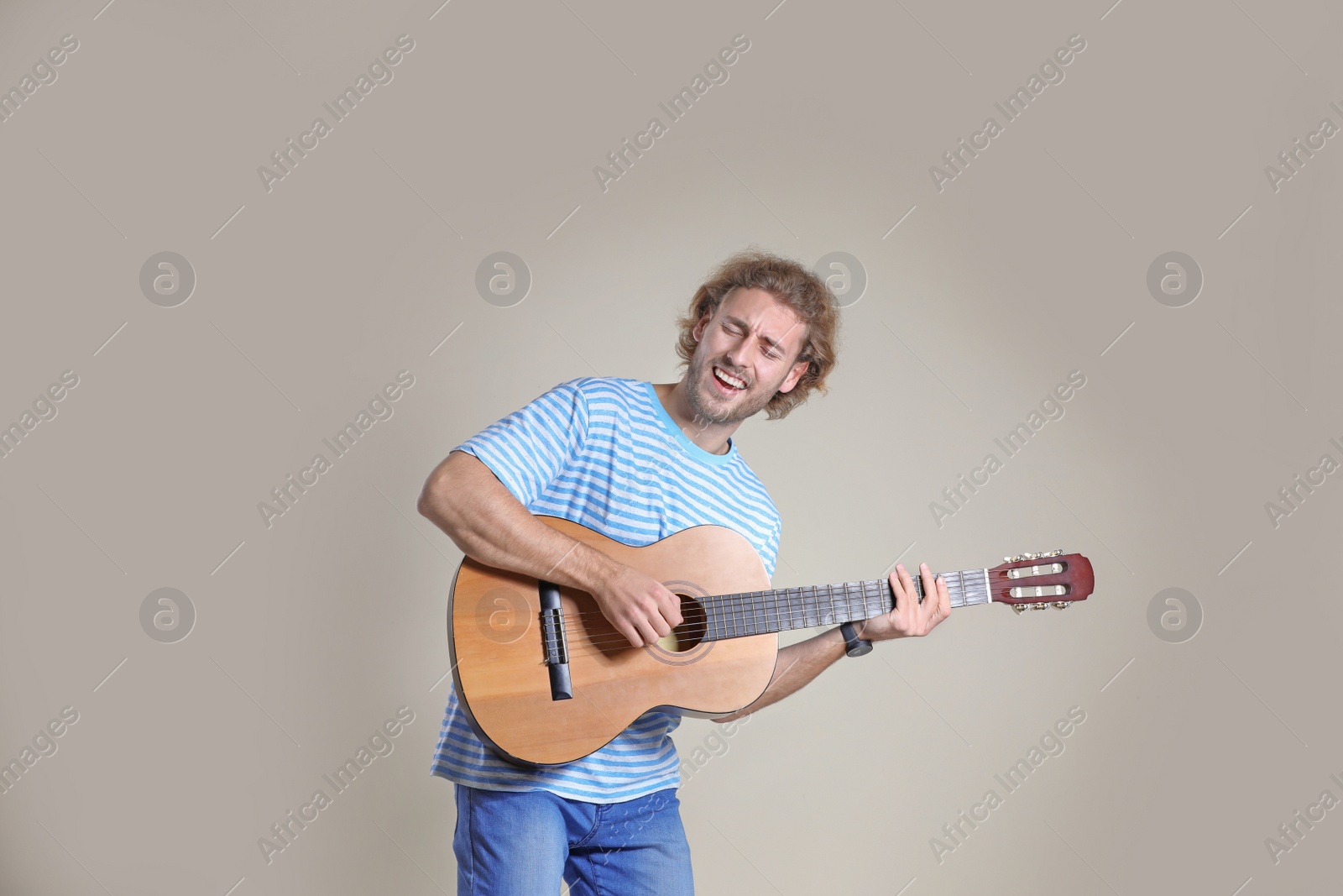 Photo of Young man playing acoustic guitar on grey background