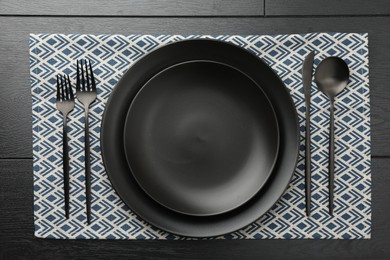 Photo of Stylish setting with cutlery and plates on black wooden table, flat lay