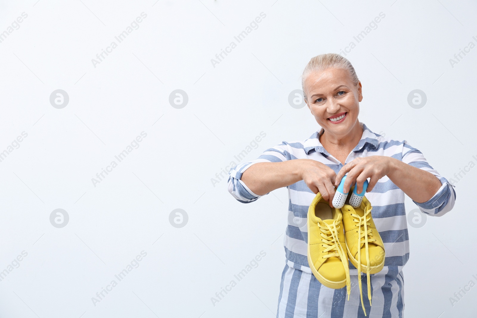 Photo of Woman putting capsule shoe freshener in footwear on white background. Space for text