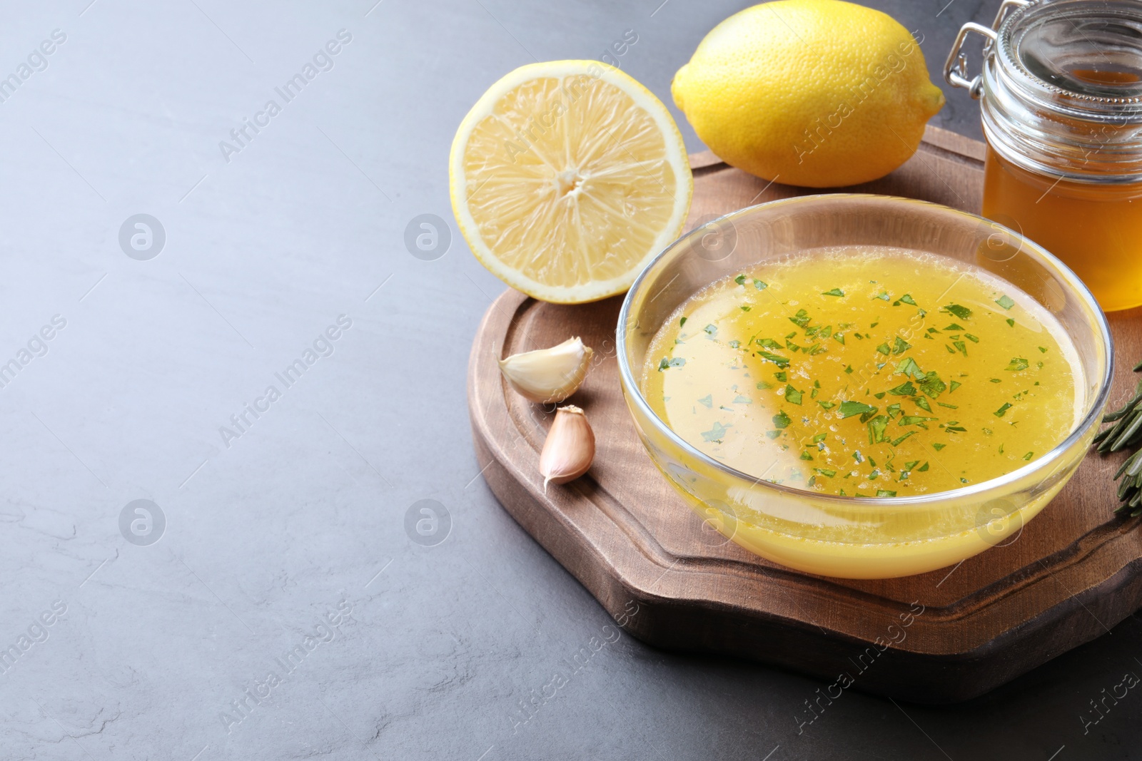 Photo of Bowl with lemon sauce and ingredients on dark table, space for text. Delicious salad dressing