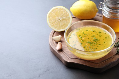 Bowl with lemon sauce and ingredients on dark table, space for text. Delicious salad dressing