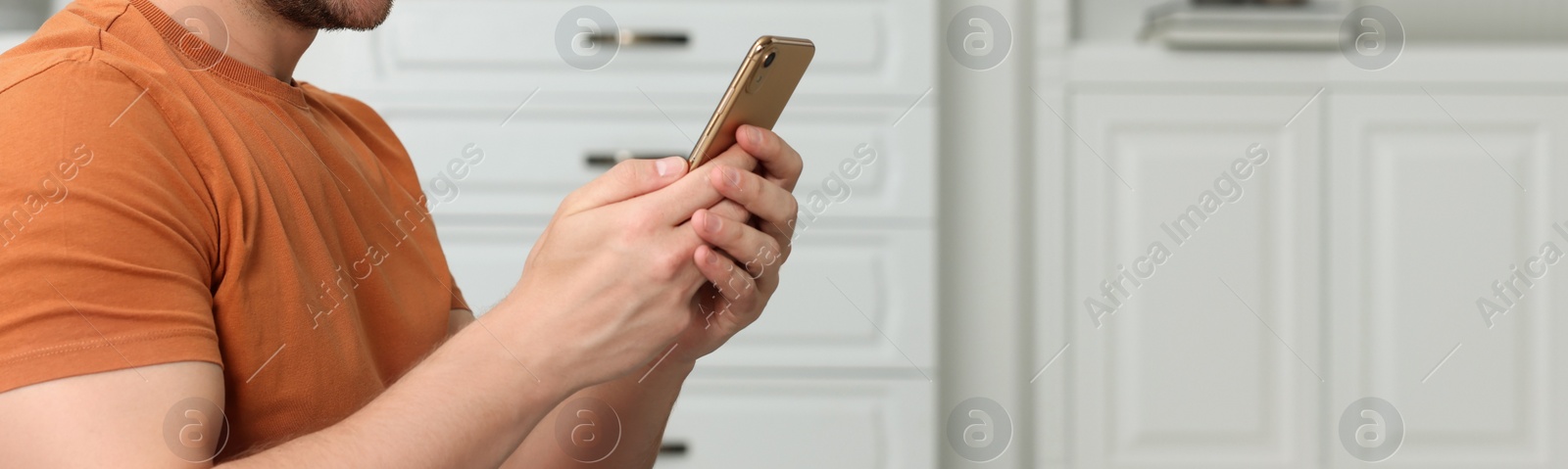 Image of Man typing message on mobile phone indoors, closeup. Banner design with space for text