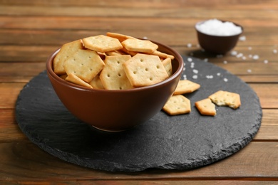 Photo of Delicious crispy crackers in bowl on wooden table
