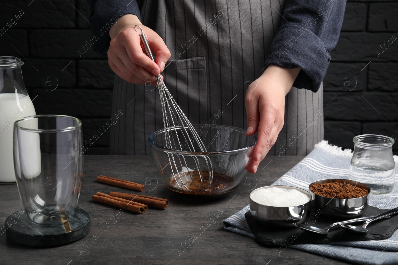 Photo of Woman whipping cream for dalgona coffee at grey table, closeup