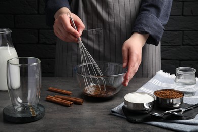 Woman whipping cream for dalgona coffee at grey table, closeup