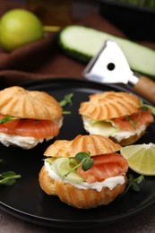 Delicious profiteroles with cream cheese, salmon and cucumber on table, closeup