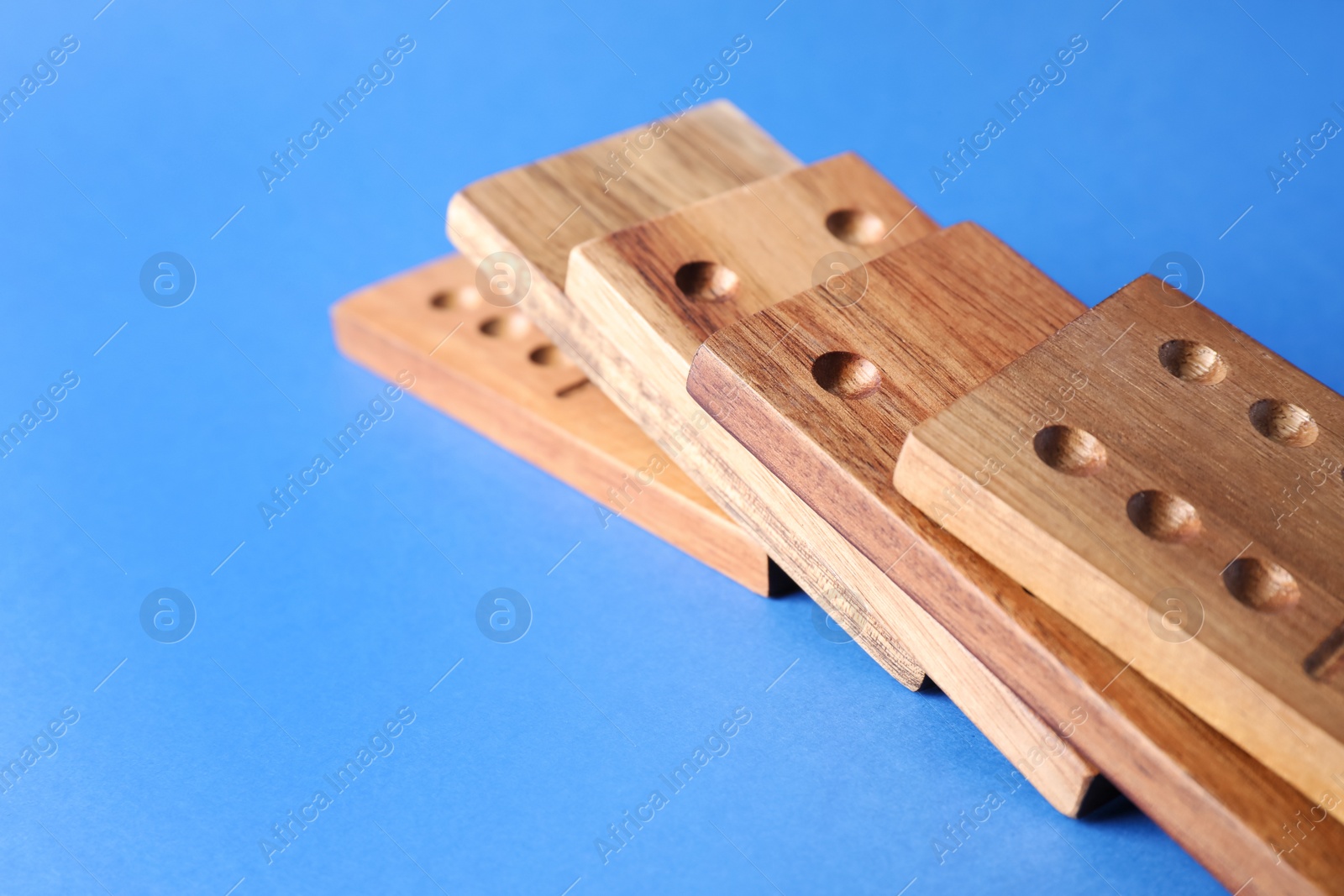 Photo of Fallen wooden domino tiles on blue background, closeup. Space for text