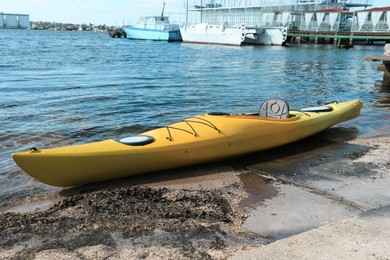 Photo of Modern kayak on beach near river. Summer camp activity