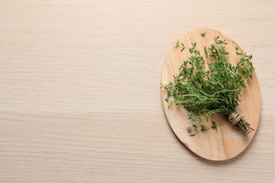 Photo of Bunch of aromatic thyme on wooden table, top view. Space for text