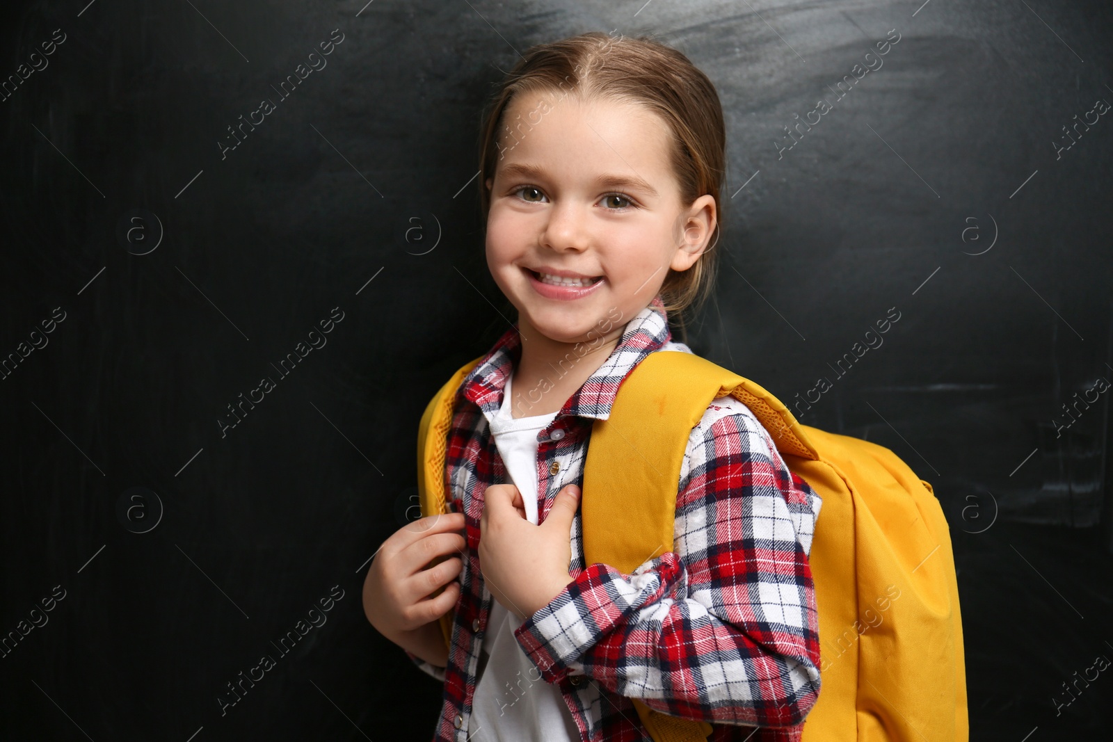 Photo of Cute little child near chalkboard. First time at school