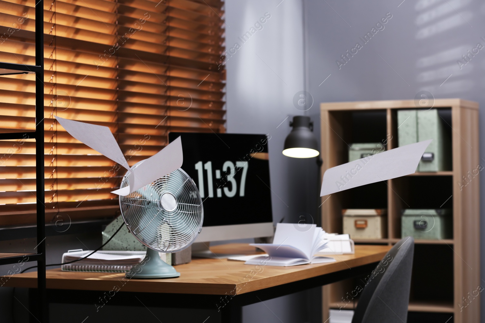 Photo of Modern electric fan and flying paper in office